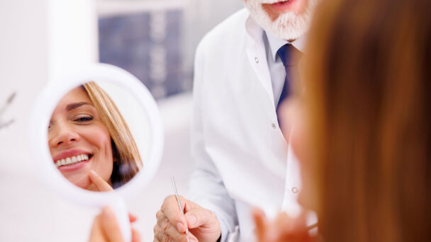 Patient Looking In The Mirror At Dentist Clinic